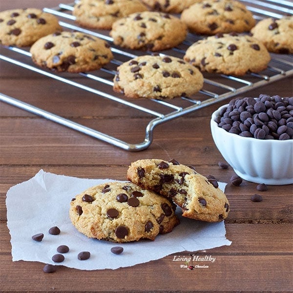 cooling rack of chocolate chip cookies in background with a bowl of chocolate chips and two cookies in foreground  