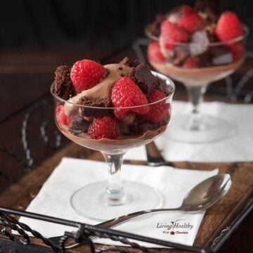 two glass serving dishes filled with raspberry chocolate brownie ice cream and fresh raspberries with a spoon in front