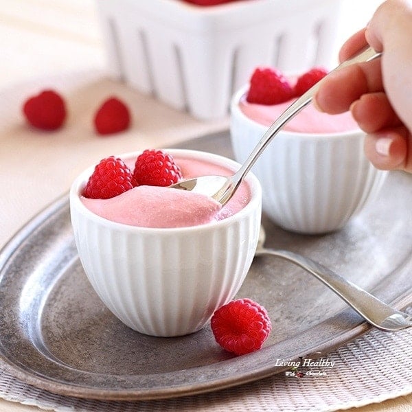 Adriana Harlan holding spoon inside small dish of Raspberry mousse with one other dish and a fresh raspberries in background