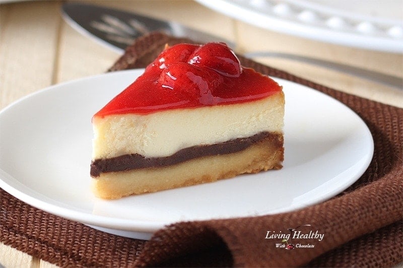 close up of a slice of white chocolate strawberry cheesecake on a white plate