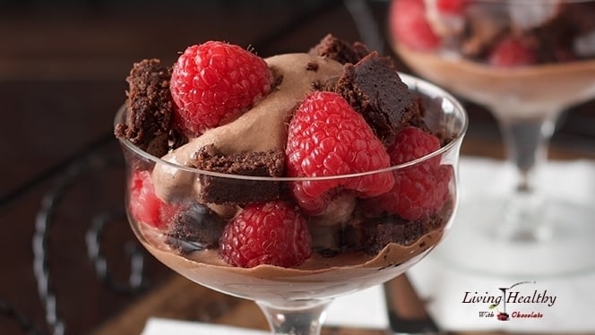 close up of a glass serving dish filled with raspberry chocolate brownie ice cream and fresh raspberries 
