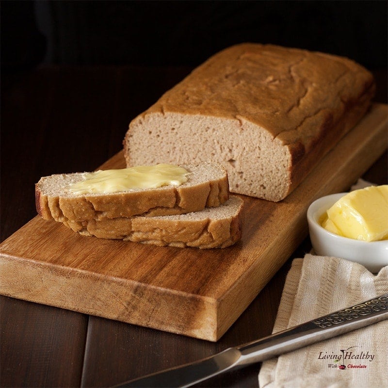 loaf of paleo sweet bread on wooden cutting board with dish of butter and knife
