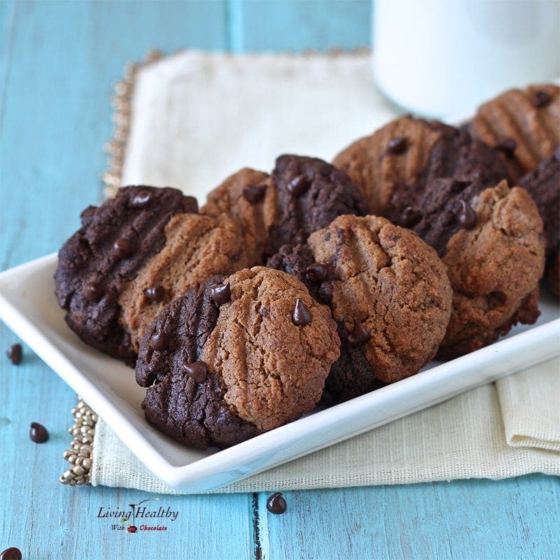 plate of two tones chewy chocolate cookies made with almond butter and a glass of milk and more cookies cooling in background