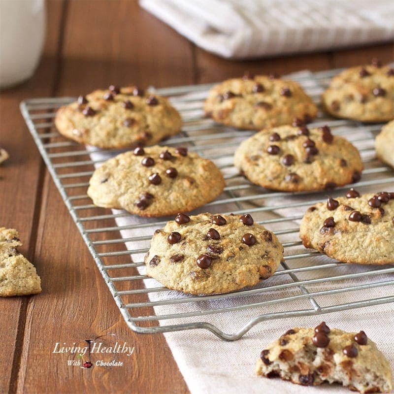 cooling rack with rows of chocolate chip cookies and one cookie broken in half in the foreground