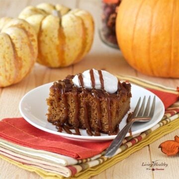 slice of paleo Caramel pumpkin cake topped with homemade whipped cream and small decretive pumpkins in the background