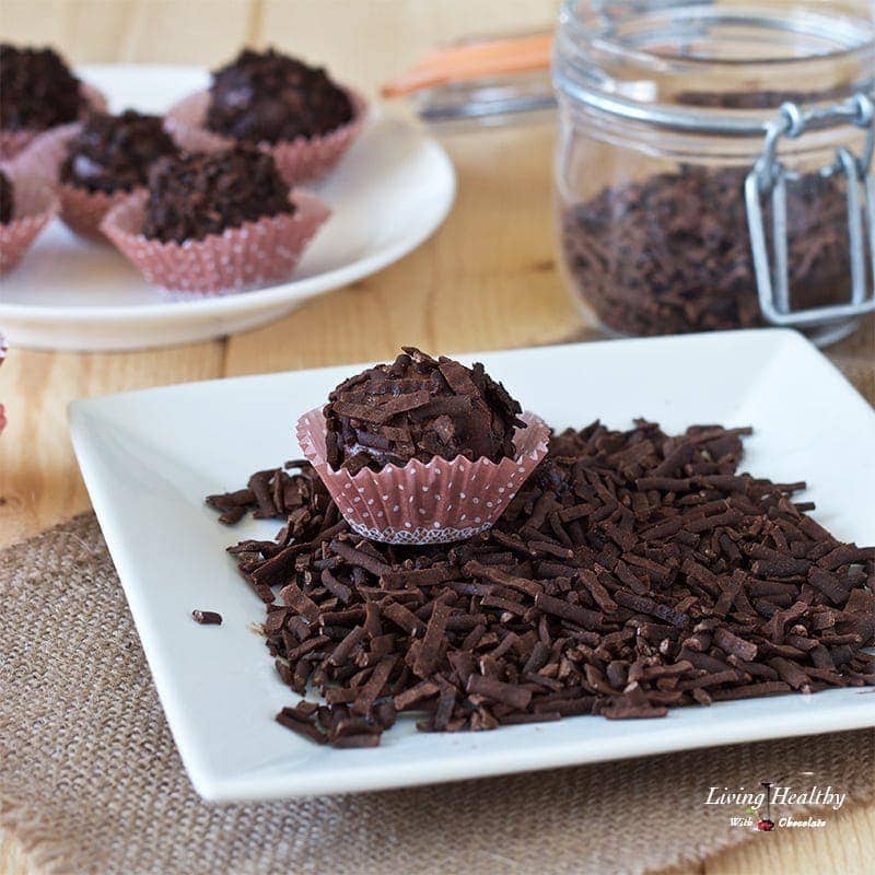 one chocolate truffle sitting on a pile of Chocolate sprinkles and more truffles in the background