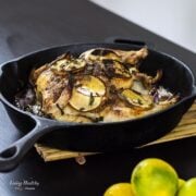 cast iron pan filled with roasted cinnamon lemon chicken topped with slices of lemon and caramelized onion