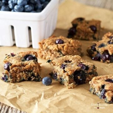 Blueberry bars cut into squares with container of blueberries in background