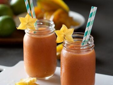 star fruit smoothies with slices of star fruit and straws in glass jars