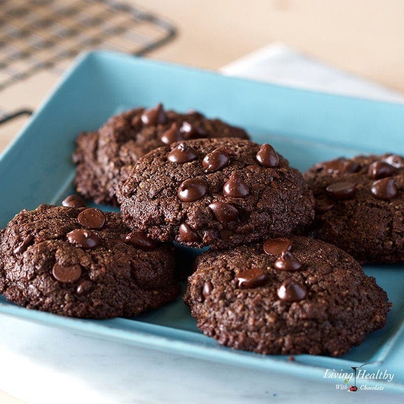 five chocolate cookies topped with chocolate chips sitting on a blue square plate