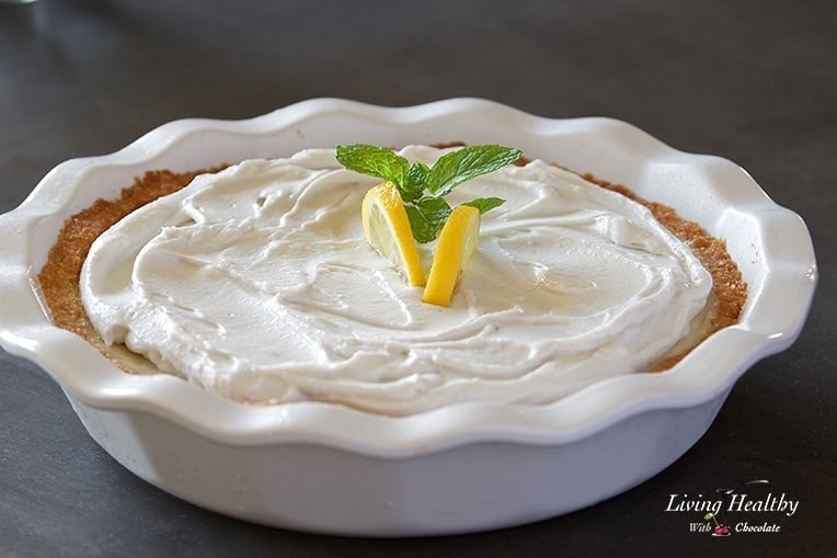 close up of a lemon cream pie topped with whipped cream and two lemon slices