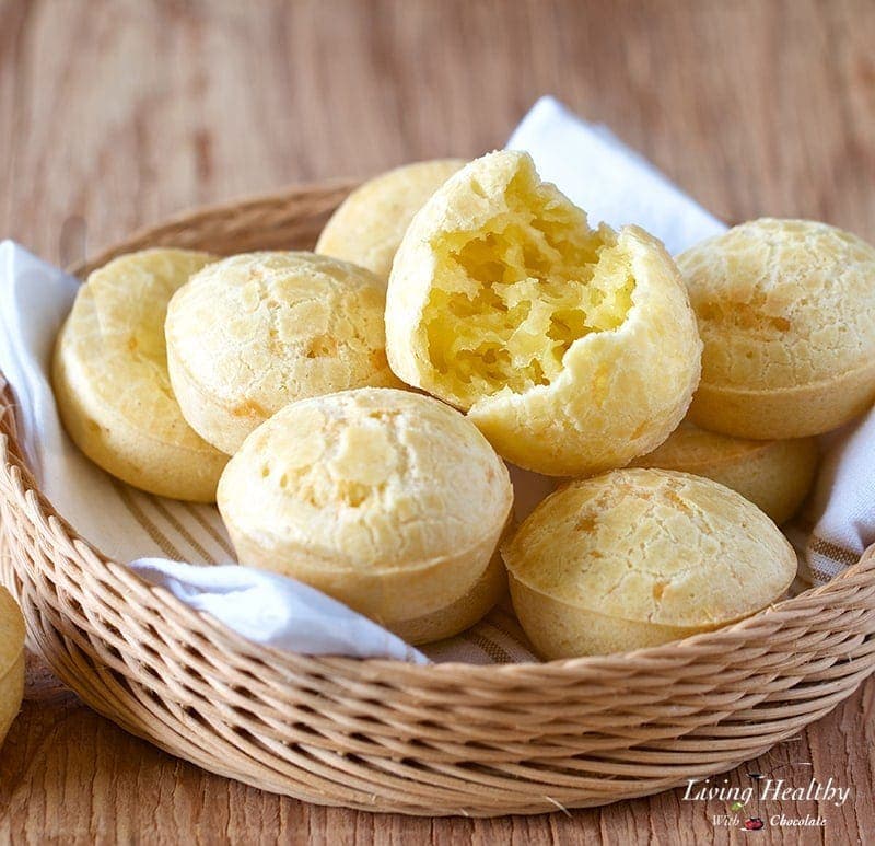 basket of Brazilian cheese bread on a table with one of the pieces split open to show the texture inside