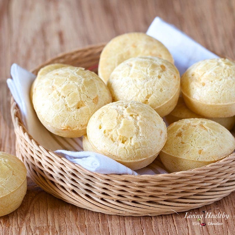 a basket filled with brazilian cheese bread and one sitting on the table next to the basket