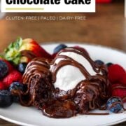 lava cake oozing with melted chocolate in the center topped with ice cream, berries and chocolate drizzle