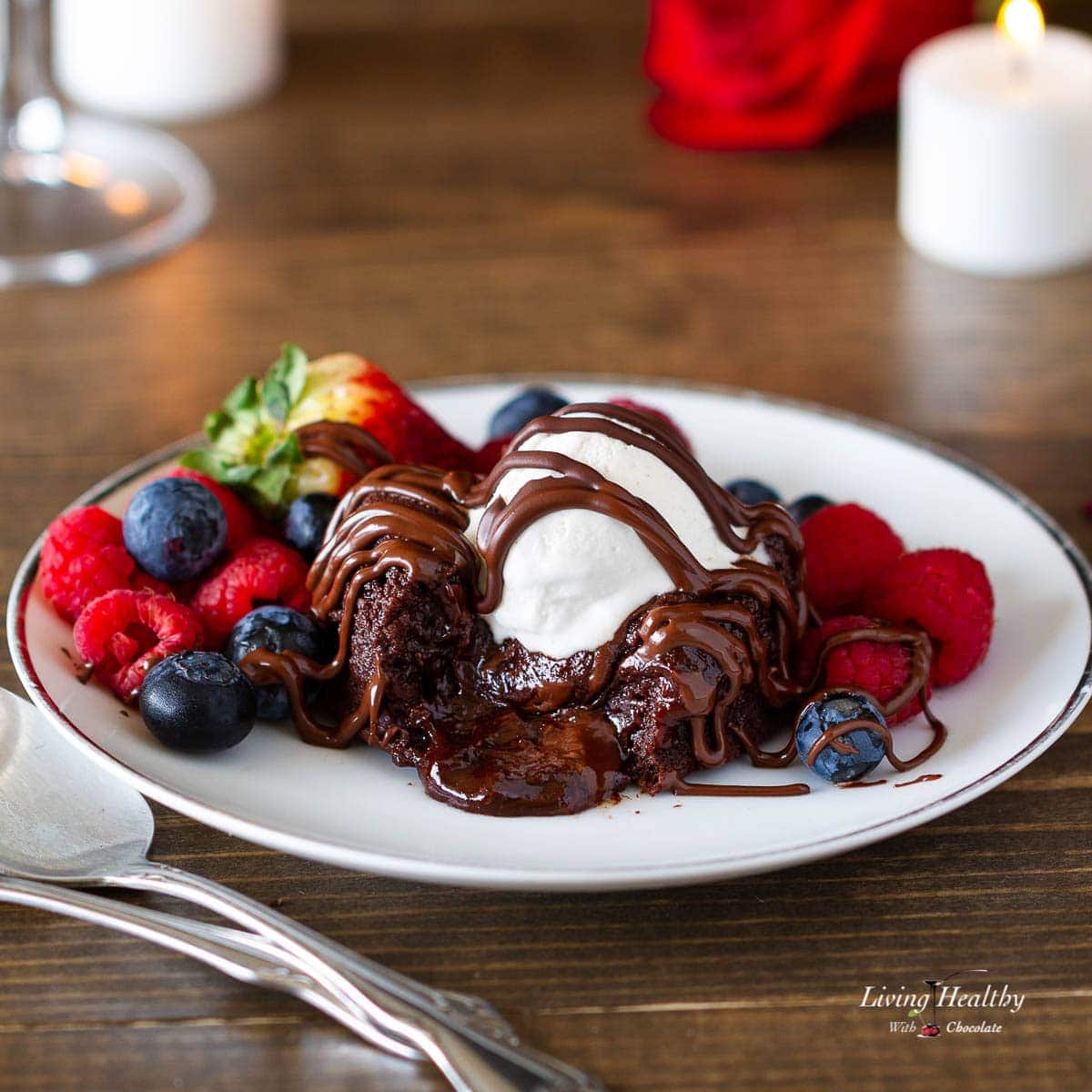 lava cake oozing with melted chocolate in the center topped with ice cream, berries and chocolate drizzle 