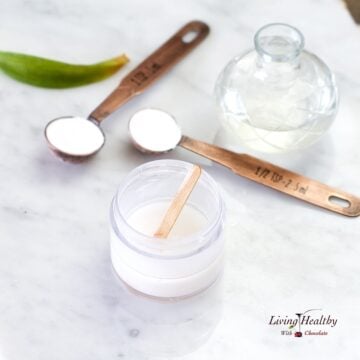 teaspoon with baking soda and oil in a jar to make natural deodorant on a marble table top