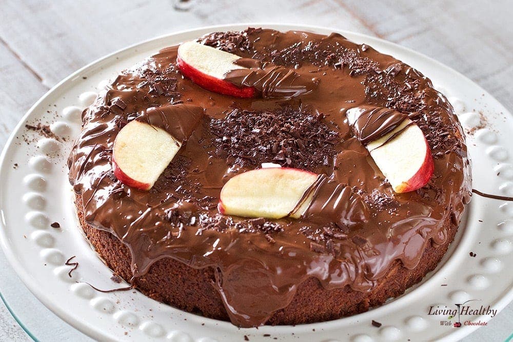 close up of chocolate cake with apple slices and chocolate shavings on top drizzled in chocolate