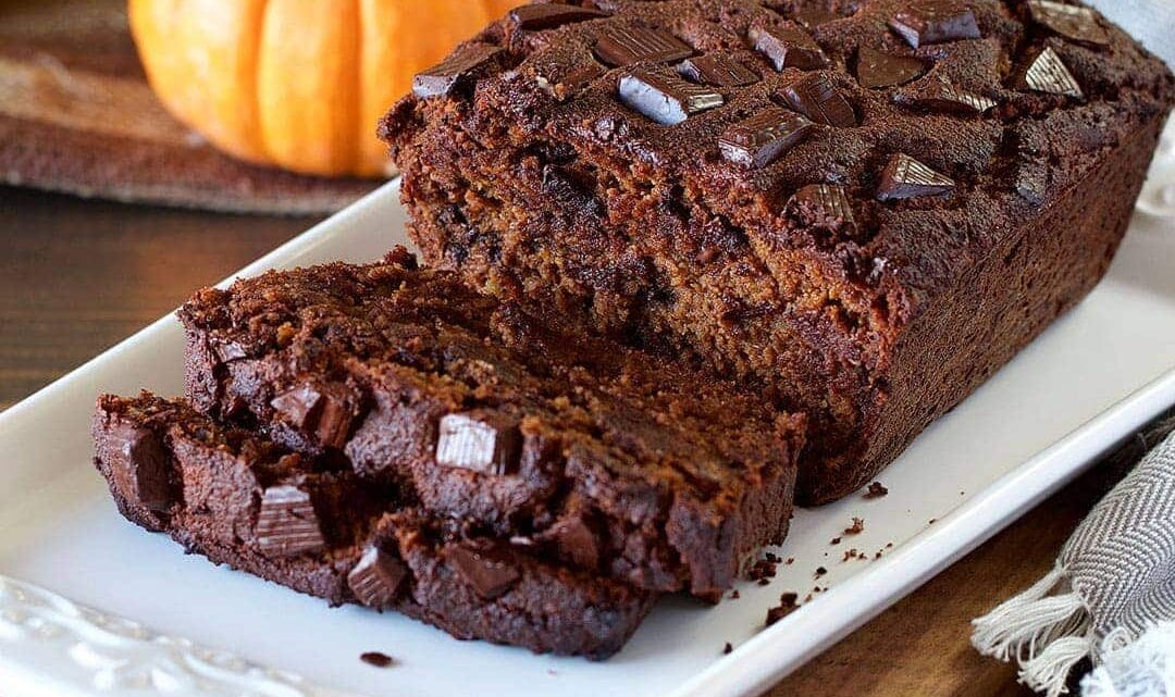 chocolate pumpkin bread displayed on a white serving dish with chocolate chunks on top of the bread