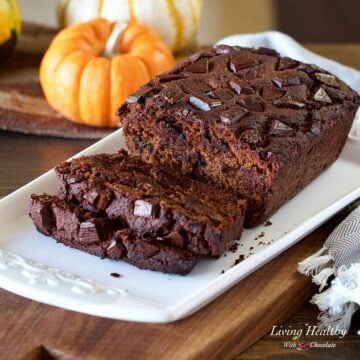 chocolate pumpkin bread displayed on a white serving dish with chocolate chunks on top of the bread