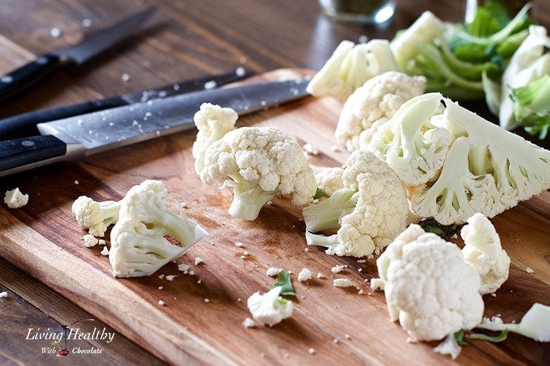 chopped cauliflower on a cutting board with knife on the left side
