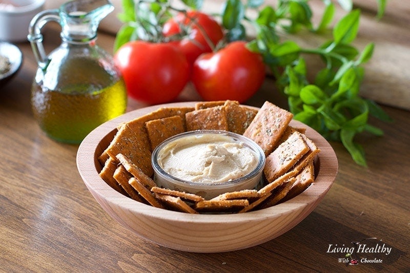 a bowl of cassava flour crackers with a small serving dish of hummus dip in the center 