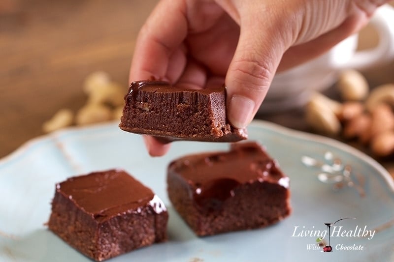 close up of Adriana Harlan holding a piece of no bake vegan brownie with two other pieces on a plate