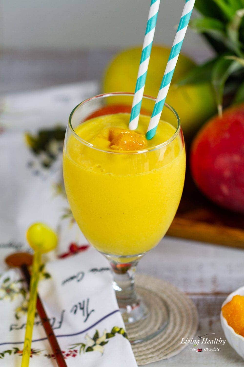 Close up of a mango smoothie in a glass with two straws