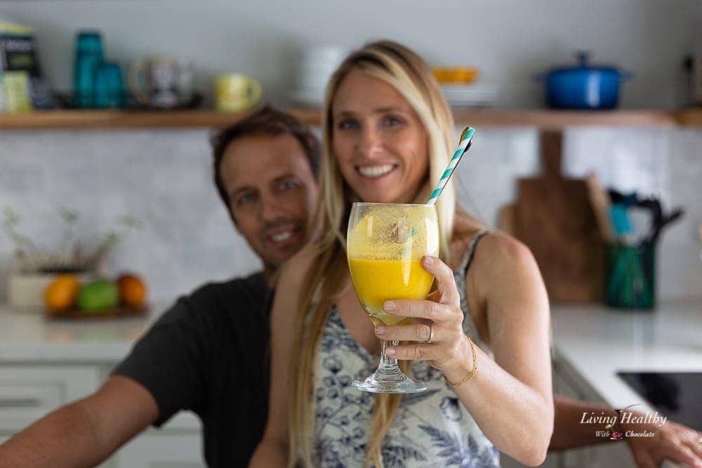 Adriana Harlan holding a glass of mango smoothie standing in front of her husband Chuck