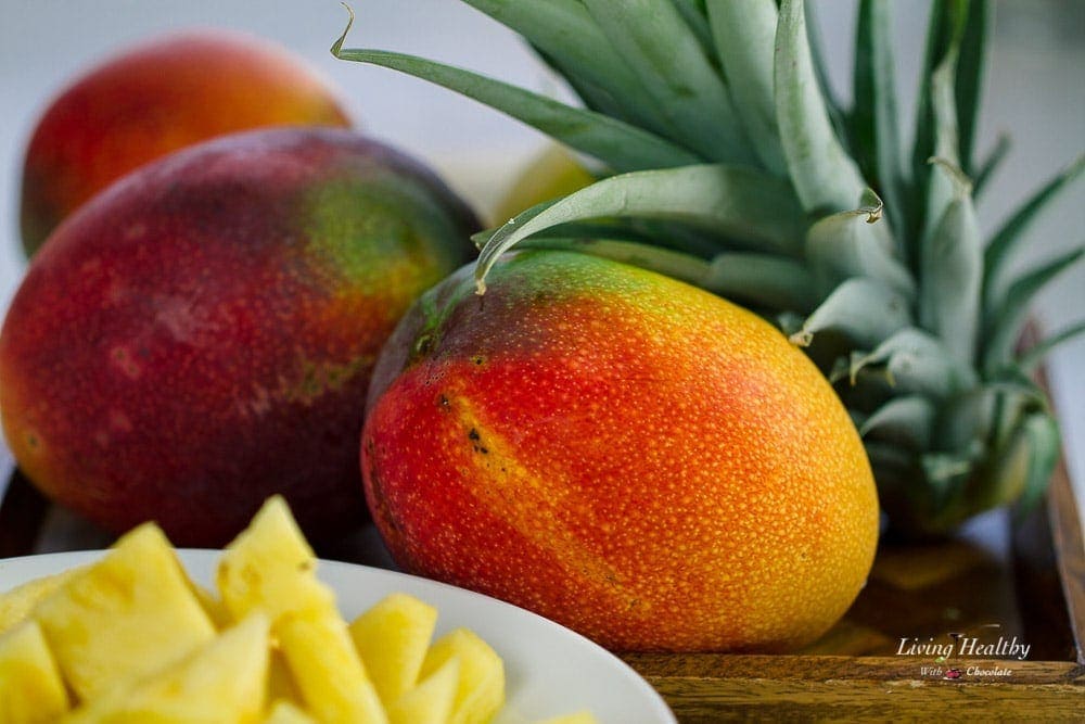 A close up of a mango and a bowl of pineapple to be used for a mango smoothie recipe