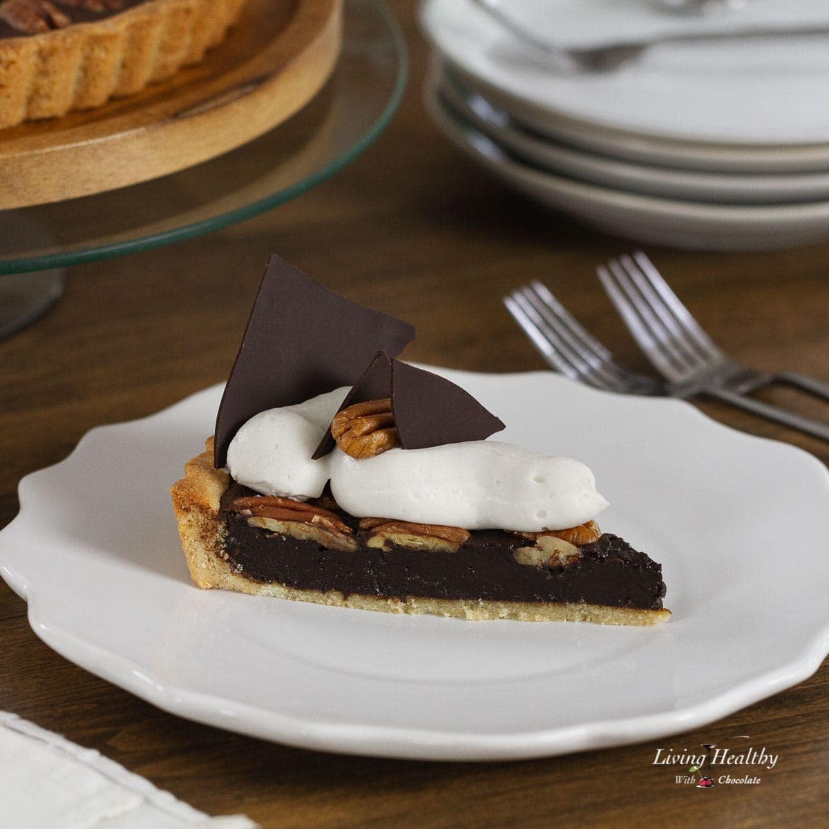 A slice of Chocolate Pecan Pie on a serving plate topped with Whipping cream and chocolate triangles