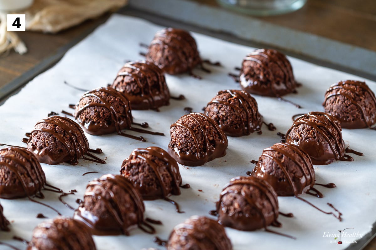 baking pan lined with parchment paper full of macaroons dipped and drizzled in chocolate