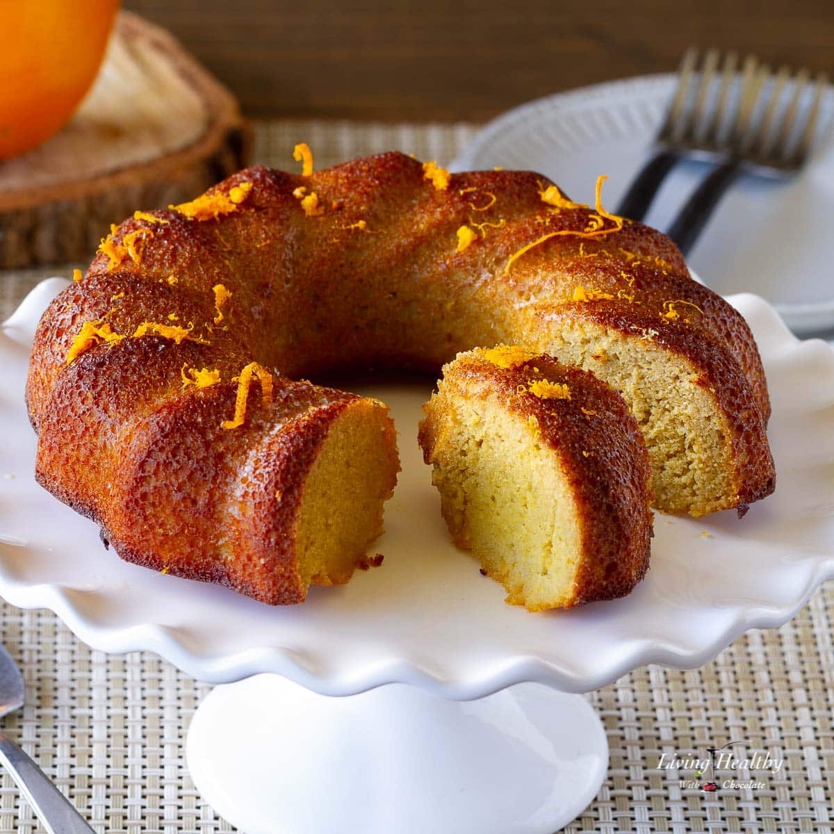 orange cake on stand with a slice in the middle showing the inside