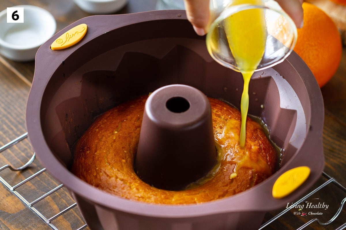 glass of orange juice being poured over the cake in the pan