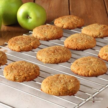 rows of apple cinnamon cookies cooling on a wire rack with green apples in background.
