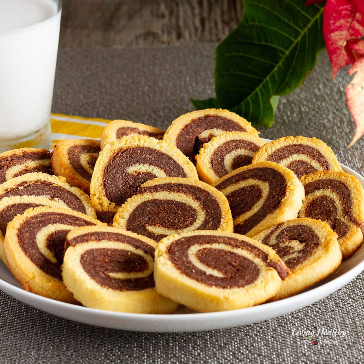 plate filled with pinwheel cookies and a glass of milk in background