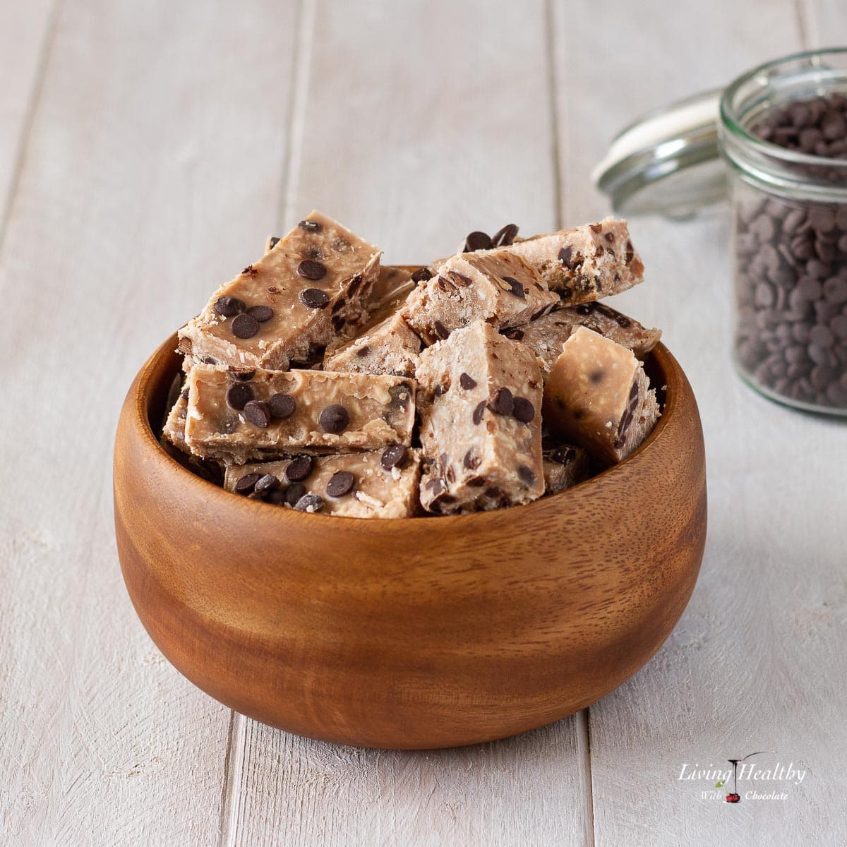 wooden bowl filled with coconut candy bars and a jar of chocolate chips in background