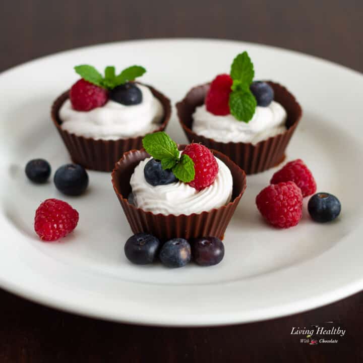 plate of three chocolate cream cups filled with homemade dairy free whipping cream and topped with fresh berries