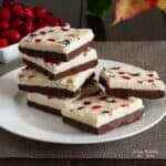 stack of paleo peppermint chocolate bark on a white plate with dish of cranberries in background.